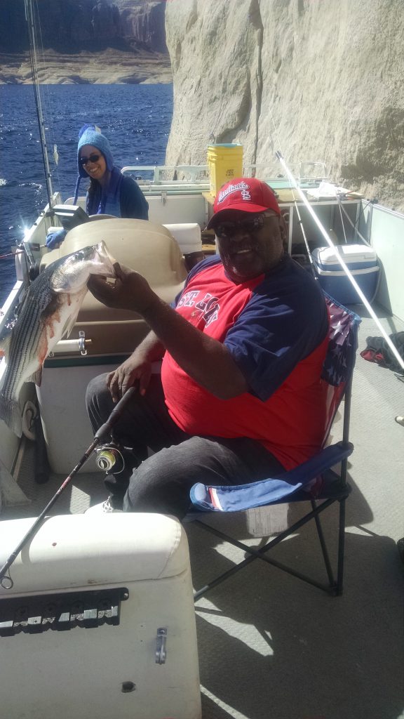 Image shows an angler proudly holding his freshly caught fish while on a fishing trip out at the lake.