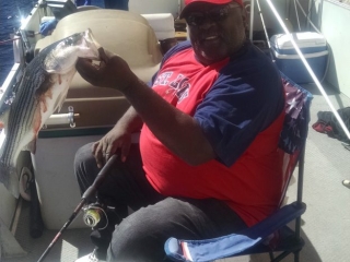 Image shows an angler proudly holding his freshly caught fish while on a fishing trip out at the lake.