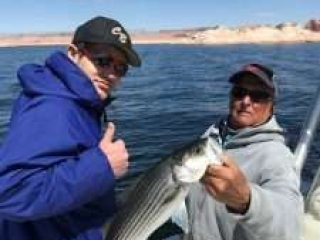 Two men, one Captain Bill the other a guest,are posing for a photo of fish the guest landed. Guest gives a thmbs up gesture.