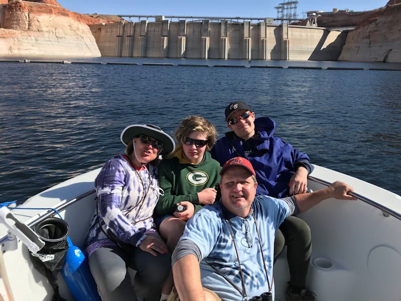 Virginia Family on Lake Powell at Dam; 5 family members sitting together in prow of boat, with Glen Canyon Dam in the background.