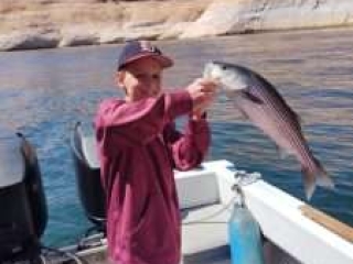 Young boy, Hank, holding up his Catch of the Day, a nice sized striped bass