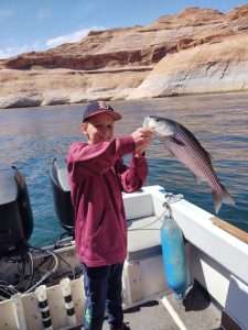 Young boy, Hank, holding up his Catch of the Day, a nice sized striped bass